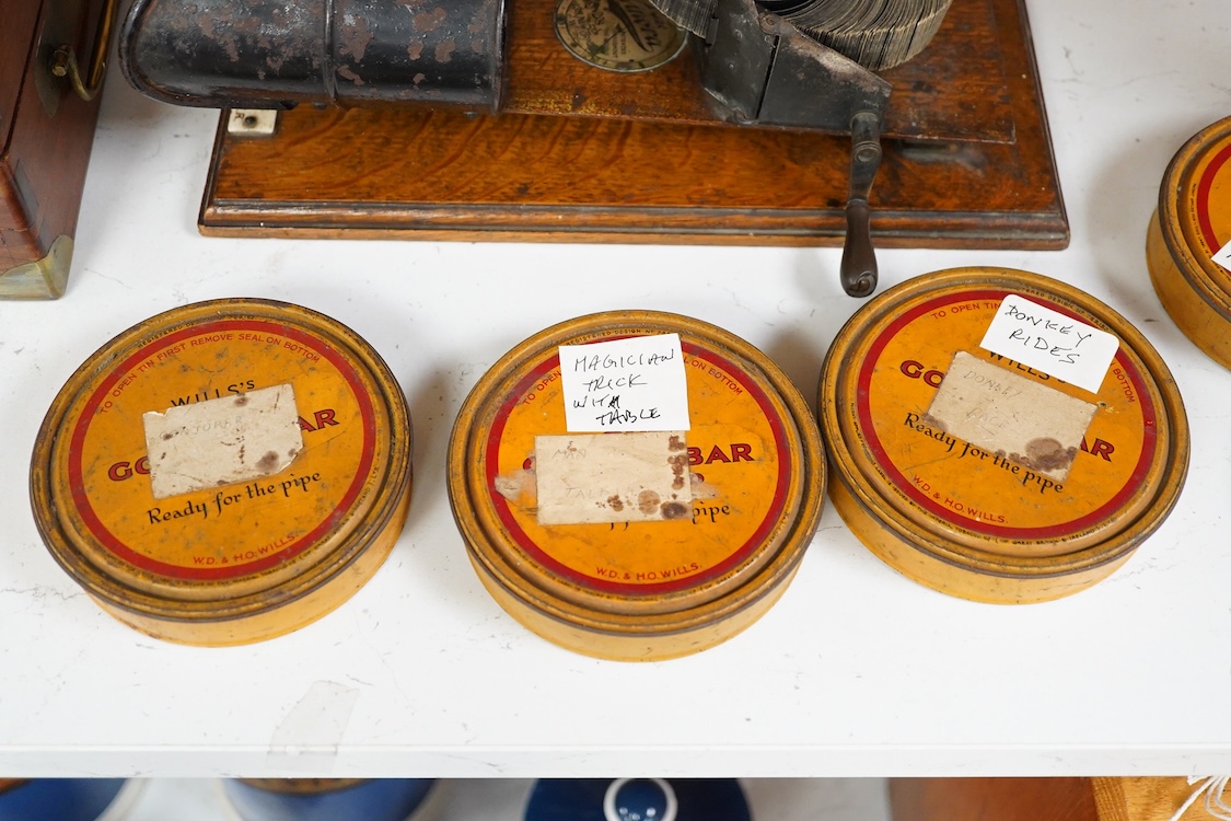 An early 20th century Kinora cinematographic viewer by Bond’s Ltd., 138 New Bond Street, c.1910, with six reels of flip card picture films, black painted steel and oak construction, with an ivory retail label for Henry’s